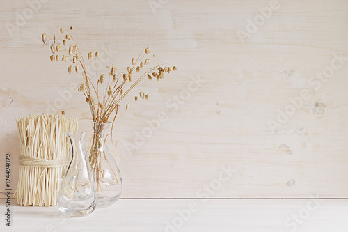 Soft home decor of  glass vase with spikelets and stalks on white wood background. Interior. photo