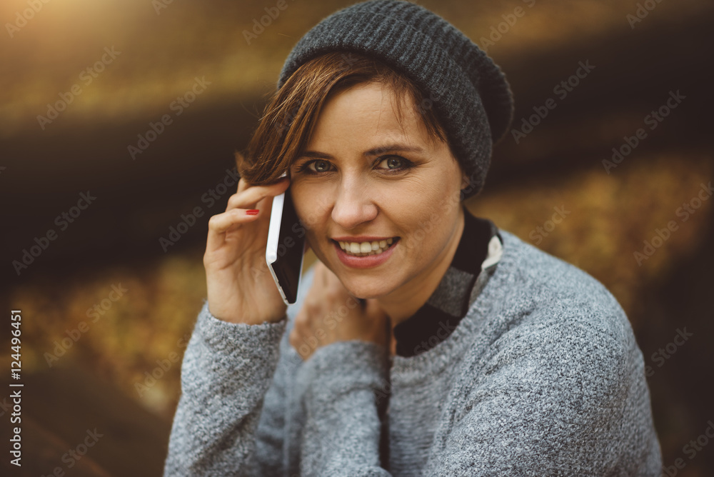 Portrait of happy, smiling woman sitting alone in the forest with smartphone. Millenial girl talking on the phone Portrait of happy, smiling woman sitting alone in the forest with smartphone. Millenial girl talking on the phone