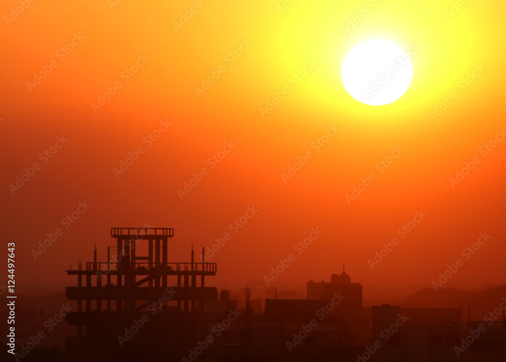 Fototapeta premium Setting sun behind construction building