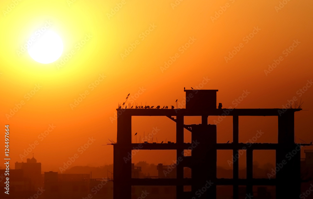Setting sun behind construction building