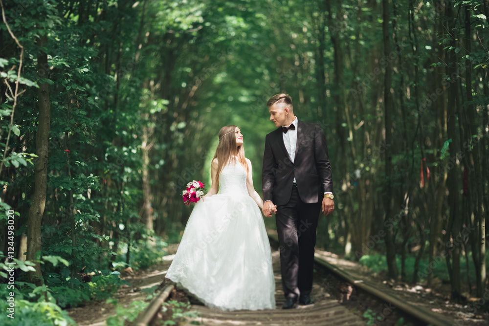 Young wedding couple, bride and groom posing on a railway track Young wedding couple, bride and groom posing on a railway track