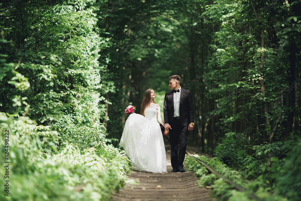 Young wedding couple, bride and groom posing on a railway track Young wedding couple, bride and groom posing on a railway track