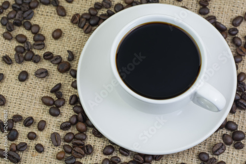 White cup with coffee drink on jute bag background