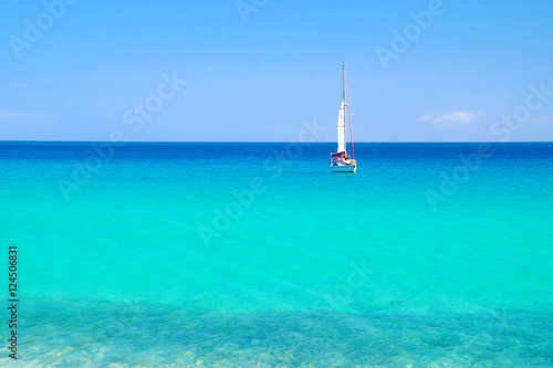 Blue sea with a white sailboat.