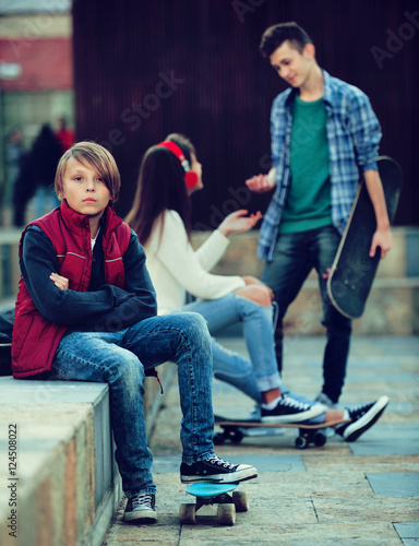 Offended boy and couple of teens apart