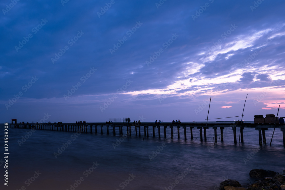 Filed wooden bridge into the sea at sunset in Thailand