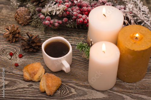 Cup of coffee, cookies, candle, fir branch in snow on wooden background
