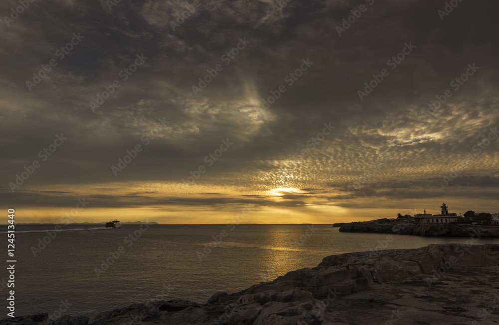 Amazing sunset over the sea with a ship and  lighthouse in foreground. Menorca, Spain