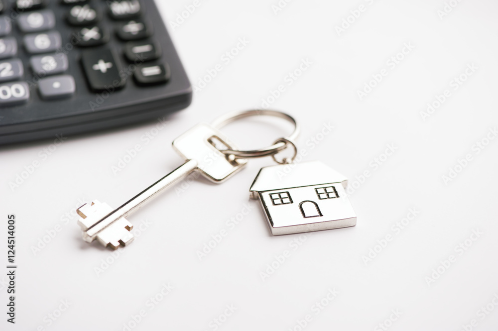 Key and house-shaped keyring and calculator - mortgage concept Key and house-shaped keyring and calculator - mortgage concept