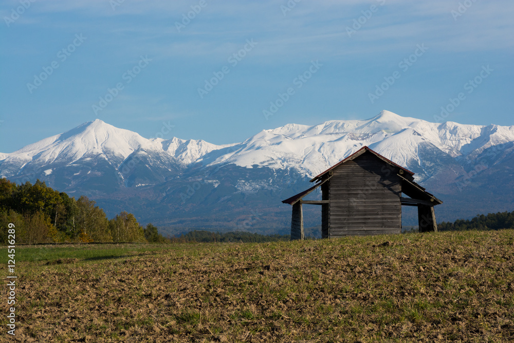 秋の雪山と農作業小屋