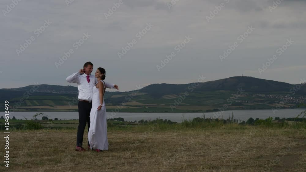 A wedding couple embraces and kisses with the Moravian countryside and Palava behind them. They share a laugh after the exaggerated kiss. In southern Czech Republic. 4k. In slow motion. A wedding couple embraces and kisses with the Moravian countryside and Palava behind them. They share a laugh after the exaggerated kiss. In southern Czech Republic. 4k. In slow motion.
