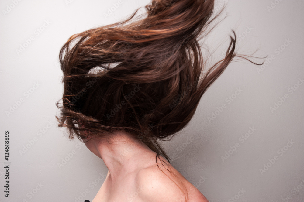 Fototapeta premium Stop action photograph of a beautiful woman with brunette hair creating motion with her hair.
