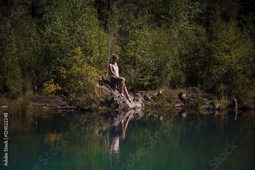 Young woman sitting near blue mountain lake
