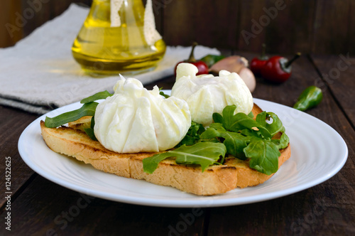 Boiled eggs in a pouch (poached) on crispy toast and green arugula leaves. Dietary breakfast.