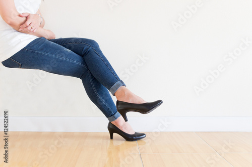 Young office Woman blue jeans Wearing High-heeled shoes ,sitting cross-legged On a white background