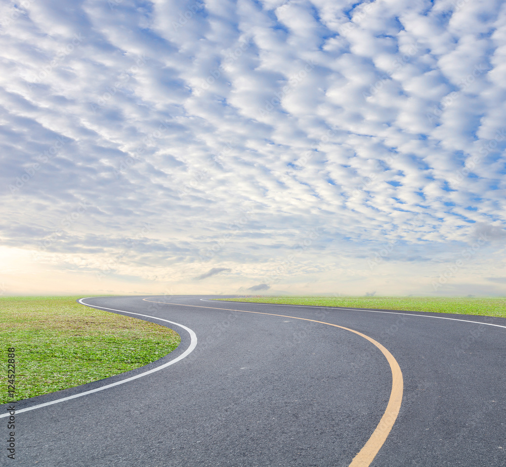 road curve with green grass and blue sky white cloud background.