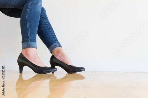 Young office Woman blue jeans Wearing High-heeled shoes ,sitting cross-legged On a white background