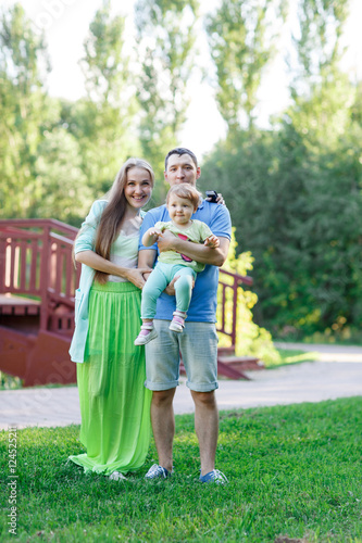Cheerful family with daughter in park next to wooden bridge
