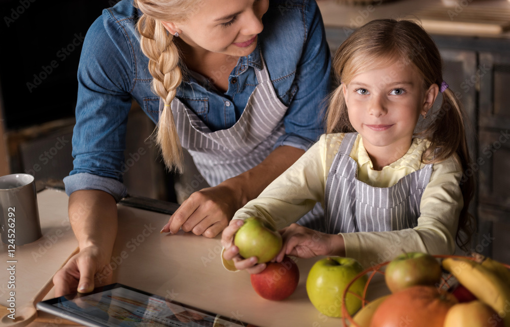 Fototapeta premium Cute girl having fun with her mother in the kitchen