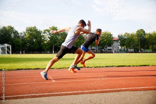 Two sports fast-running men on track outdoors
