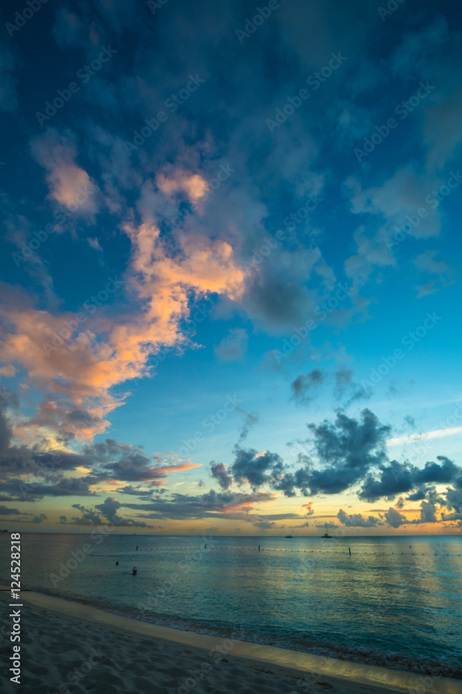 sunset on a tropical beach in the caribbean with cloudy skies and calm waters