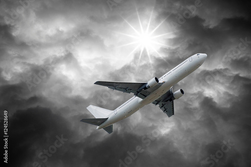 airplane on dark stormy sky and Sun