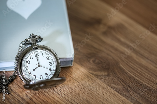Luxury pocket watch over the book on the wooden table with copy space