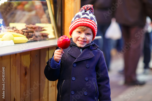 little kid boy eating crystalized apple on Christmas market