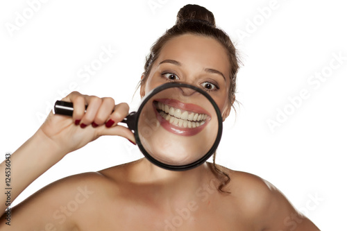 woman shows her smile through a magnifying glass