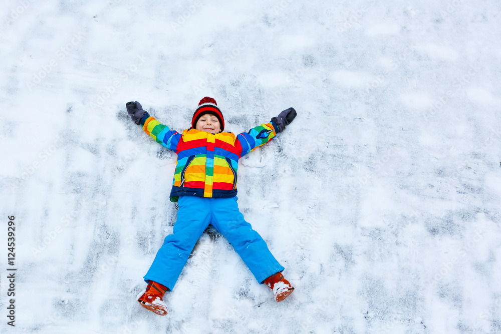Little kid boy making snow angel in winter, outdoors Little kid boy making snow angel in winter, outdoors