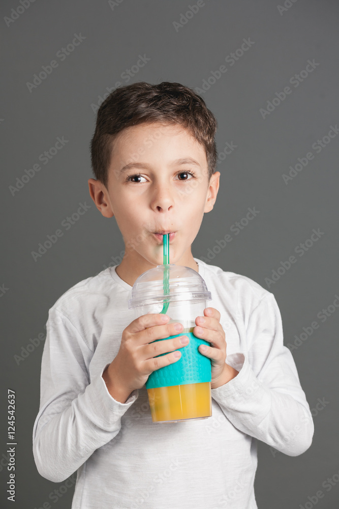 Little funny boy drinking a fresh juice through a straw Little funny boy drinking a fresh juice through a straw
