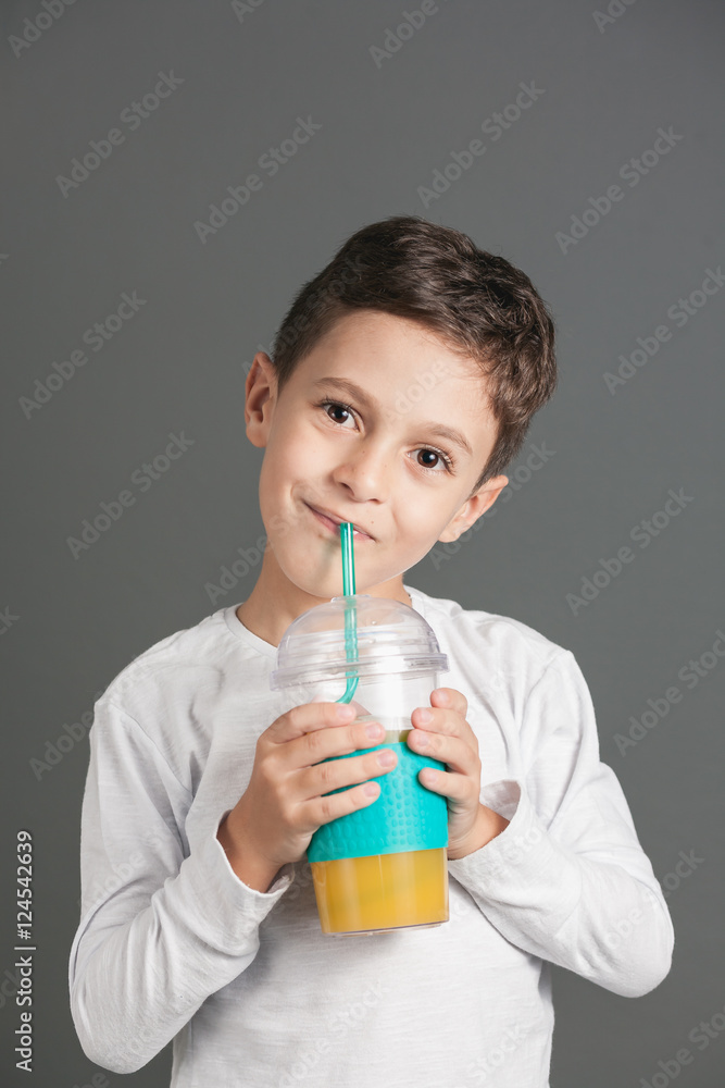 Little funny boy drinking a fresh juice through a straw