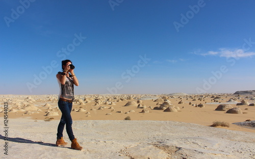 Young beautiful girl takes a picture in the middle of the amazing White desert close to Farafra oasis in Egypt © nachosuko