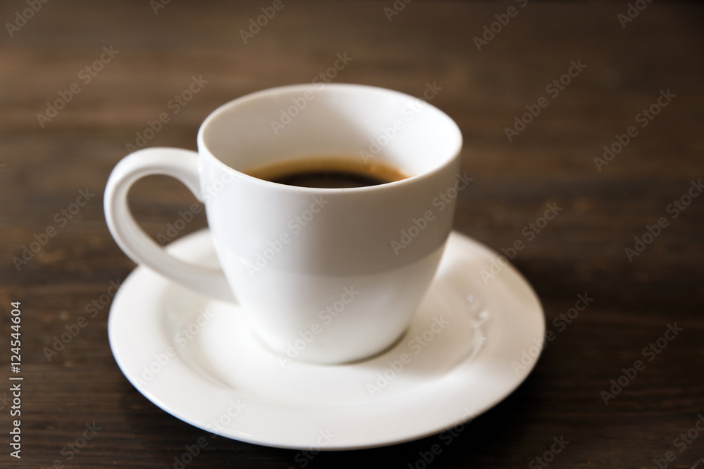 A white cup of black coffee on the wooden table. Selective focus, small depth of fieild.