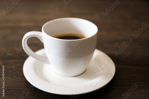 A white cup of black coffee on the wooden table. Selective focus  small depth of fieild.