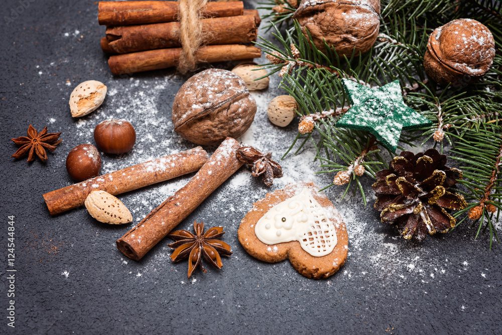 Christmas decoration, fir tree branches with nuts, gingerbread and  spices in snow  on  dark background.