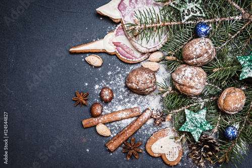Christmas decoration, fir tree branches with nuts and spices on dark background. Top view