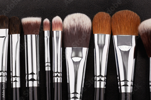 Makeup brushes set on black leather background