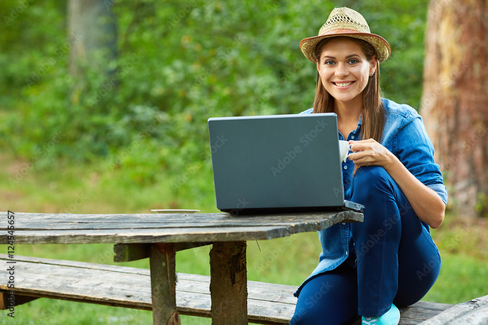  woman drinking coffee in garden and working with laptop.