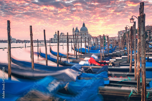 Gorgeous sunset over Grand Canal and Basilica Santa Maria della Salute with moving gondolas, Venice, Italy