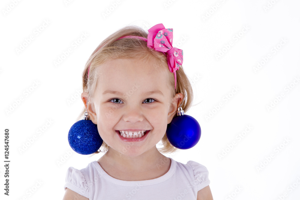blond toddler girl portrait blue Christmas balls as earrings. smile joke new year blond toddler girl portrait blue Christmas balls as earrings. smile joke new year