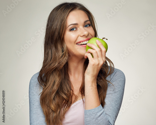 smiling woman bites green apple.