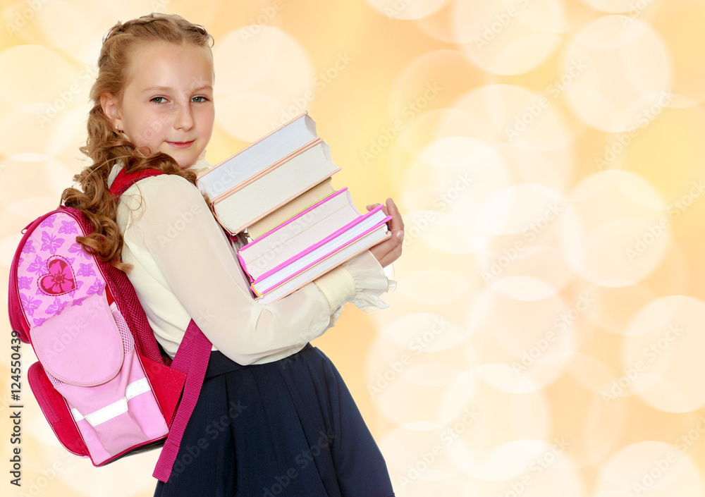 Girl schoolgirl with a satchel behind shoulders and books in han Girl schoolgirl with a satchel behind shoulders and books in han