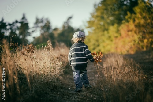 Happy little boy playing outdoor in beautiful autumn scenery