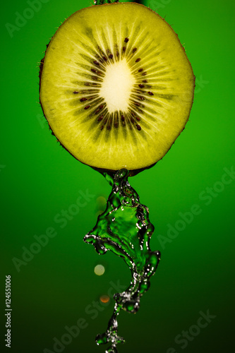 Ripe kiwifruit with drops of water isolated on green background