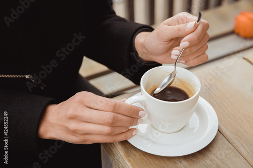 Hands with a spoon and a cup of black coffee