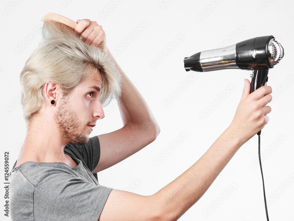 Young man drying hair with hairdryer Young man drying hair with hairdryer