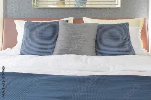 Dark blue and gray pillow on bed with brown leather headboard