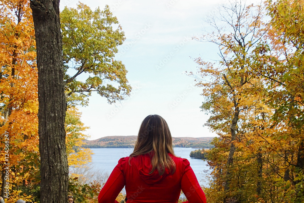 Woman in red looking out over lake in Autumn Woman in red looking out over lake in Autumn