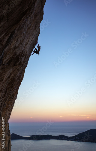 Rock climber on overhanging cliff at sunset. Kalymnos Island, Greece.